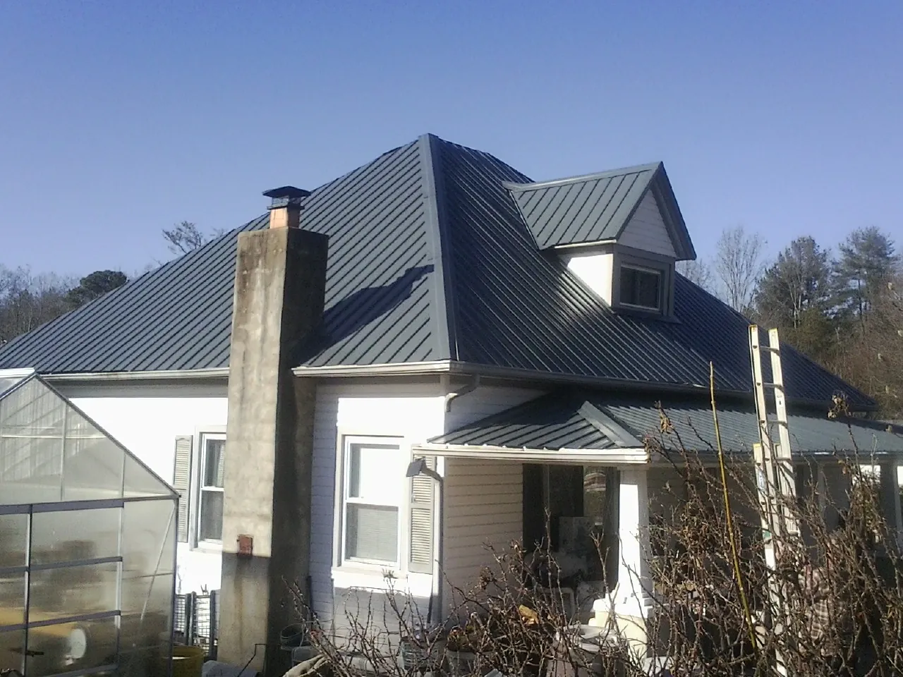 Dark blue standing seam metal roof on a white farmhouse with dormer — Slate & Tile Roof Repair by Roofing Brothers in Loch Sheldrake