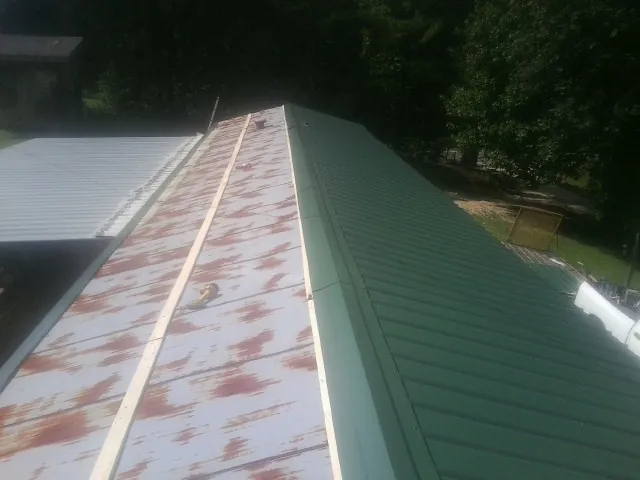 Old rusted panels beside newly installed green metal roofing — Wind Damage Roof Repair by Roofing Brothers in Loch Sheldrake
