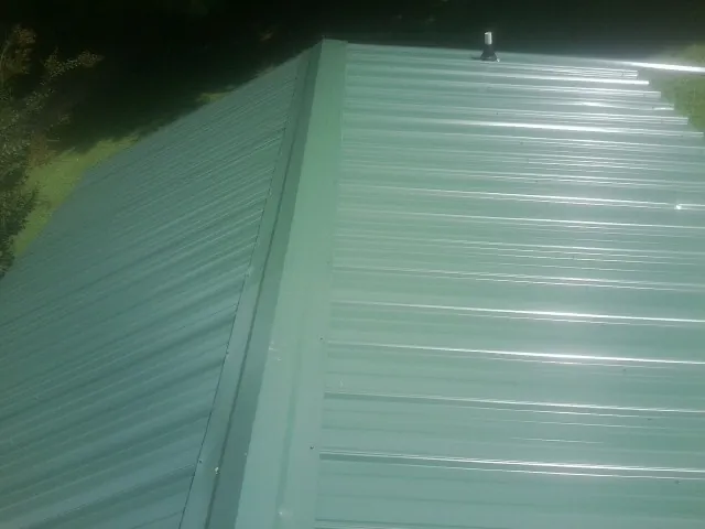 New green metal panels meeting at the ridge of a roof — Flat Roof Repair work by our crew in Loch Sheldrake