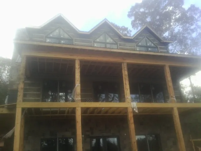 Dormers and porch framing on a large log home under construction — Roof Coating work by our crew in Loch Sheldrake