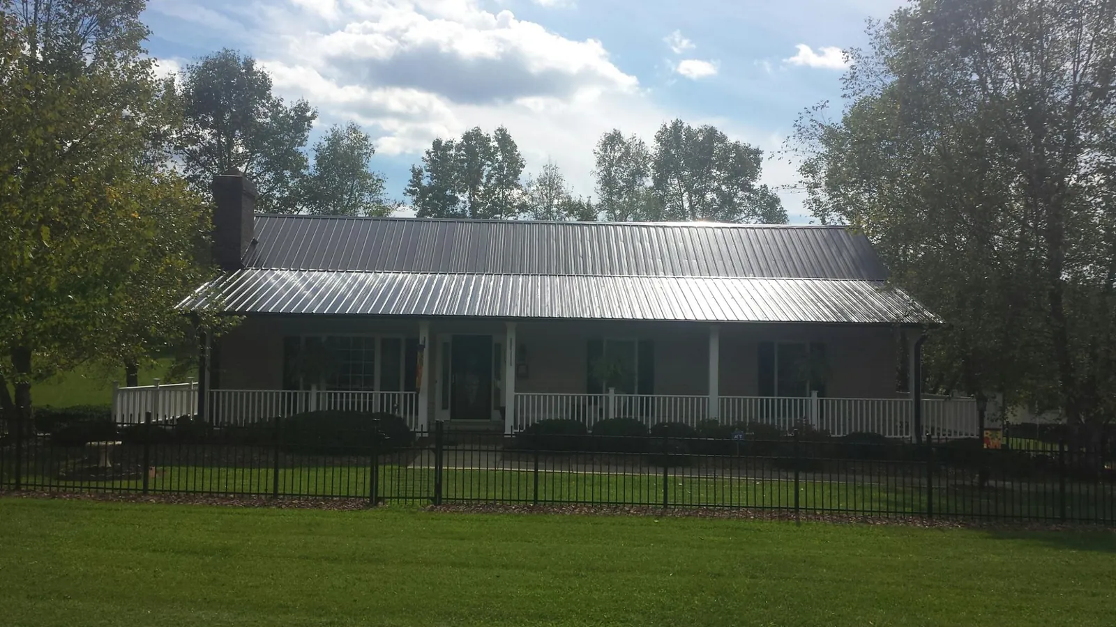 Gray metal roof on a brick ranch with a full width front porch — Gutter Guard Installation work by our crew in Loch Sheldrake