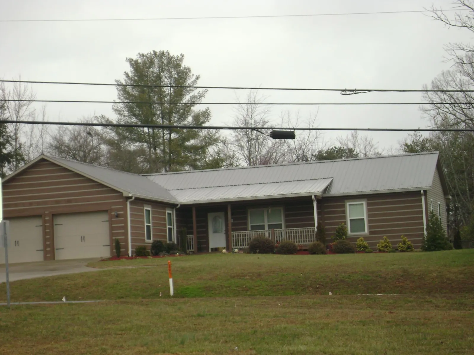 Gray metal roof on a log sided ranch home with a front porch in Loch Sheldrake