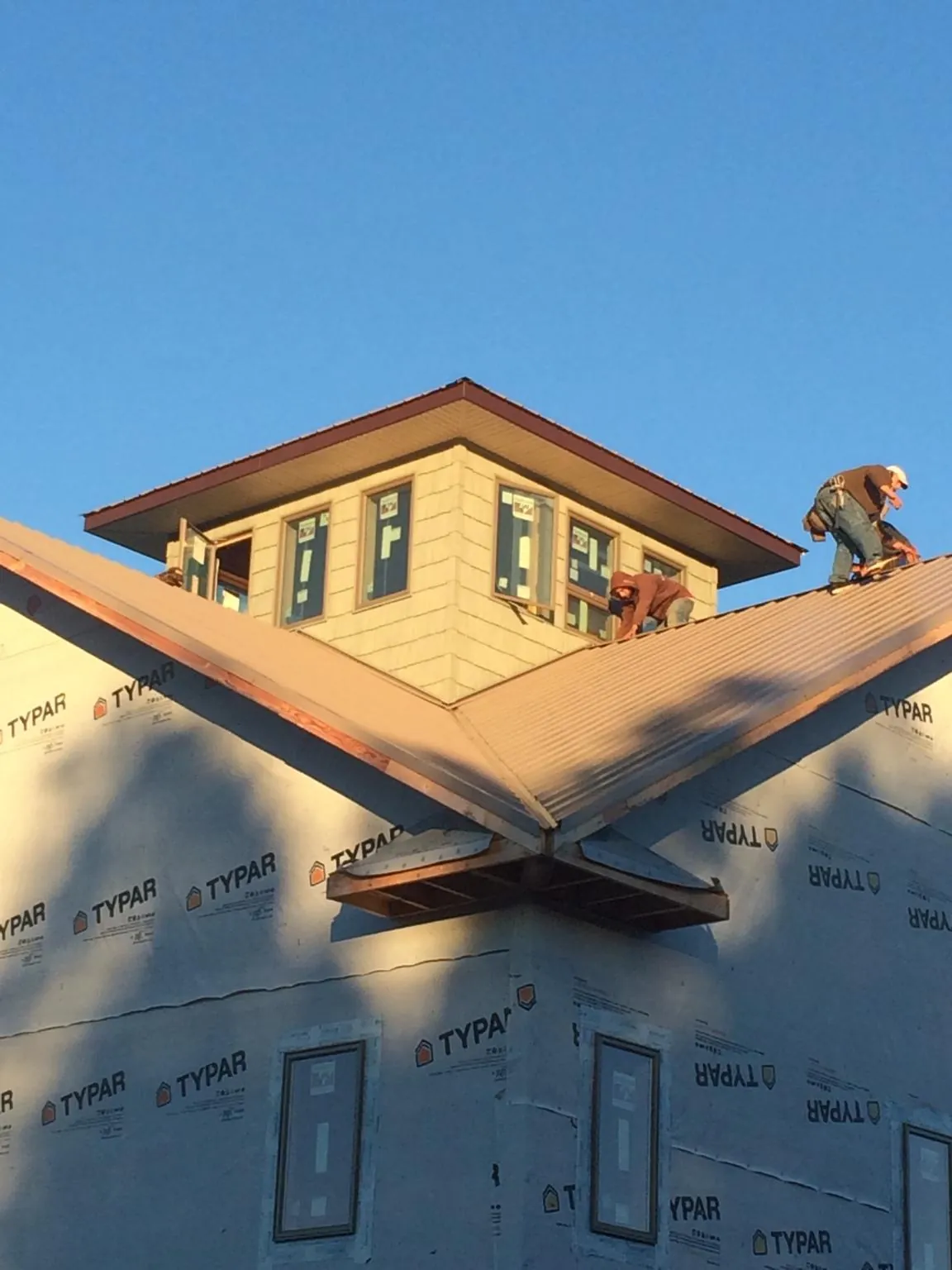 Roofers working around a rooftop cupola on a new metal roof at sunset — Roof Waterproofing in Loch Sheldrake by Roofing Brothers